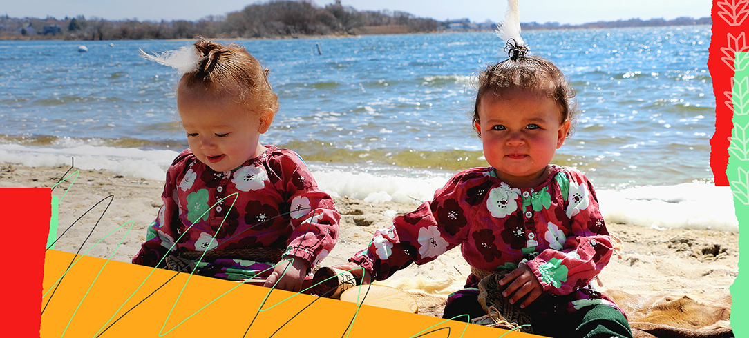 two babies sitting at the beach